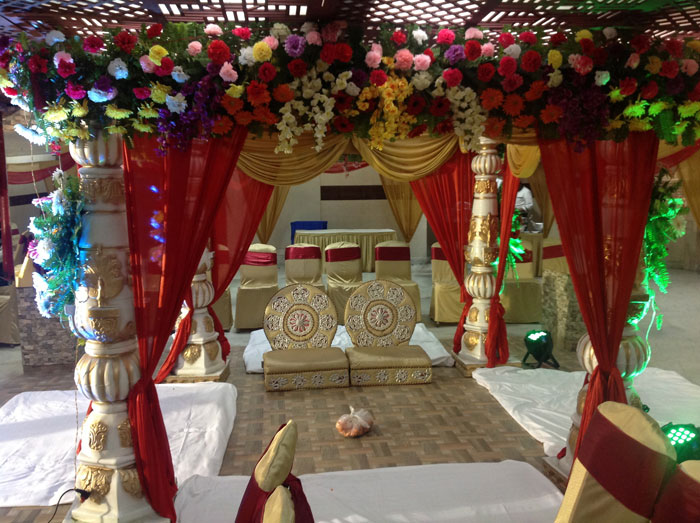 Wedding mandap at Buddha Heritage — red drapes, flower canopy, gold cushions, traditional setup